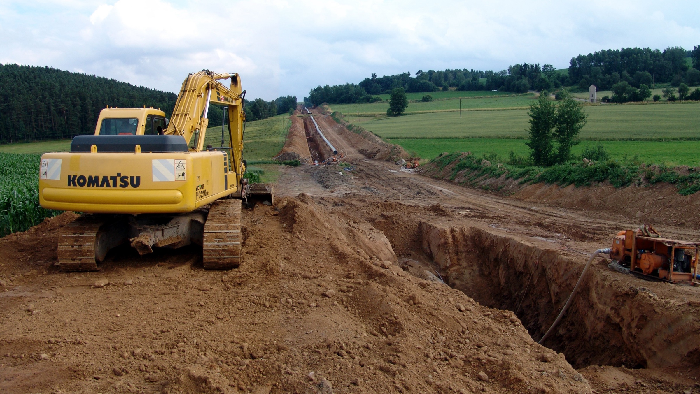 Pipeline construction: coated pipe strung along an open trench
